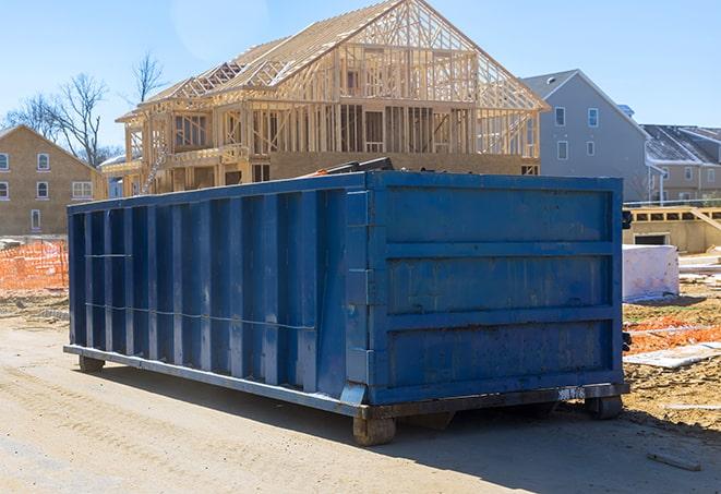 a truck hauling away a full, residential dumpster with a concrete driveway in the background